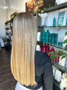 Long blonde hair with evenly distributed lighter pieces at Savoye Salon Spa