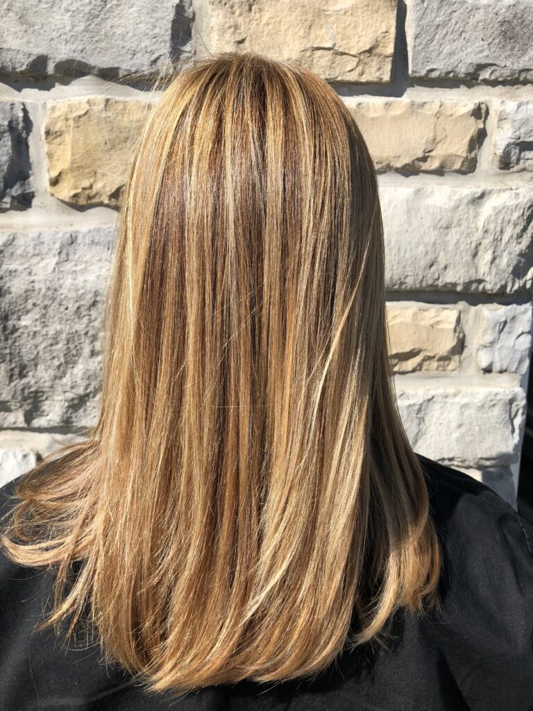 Warm dimensional hair color with lighter pieces throughout at Savoye Salon Spa